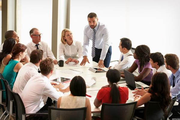Stock photo of people seated around a table at a board meeting